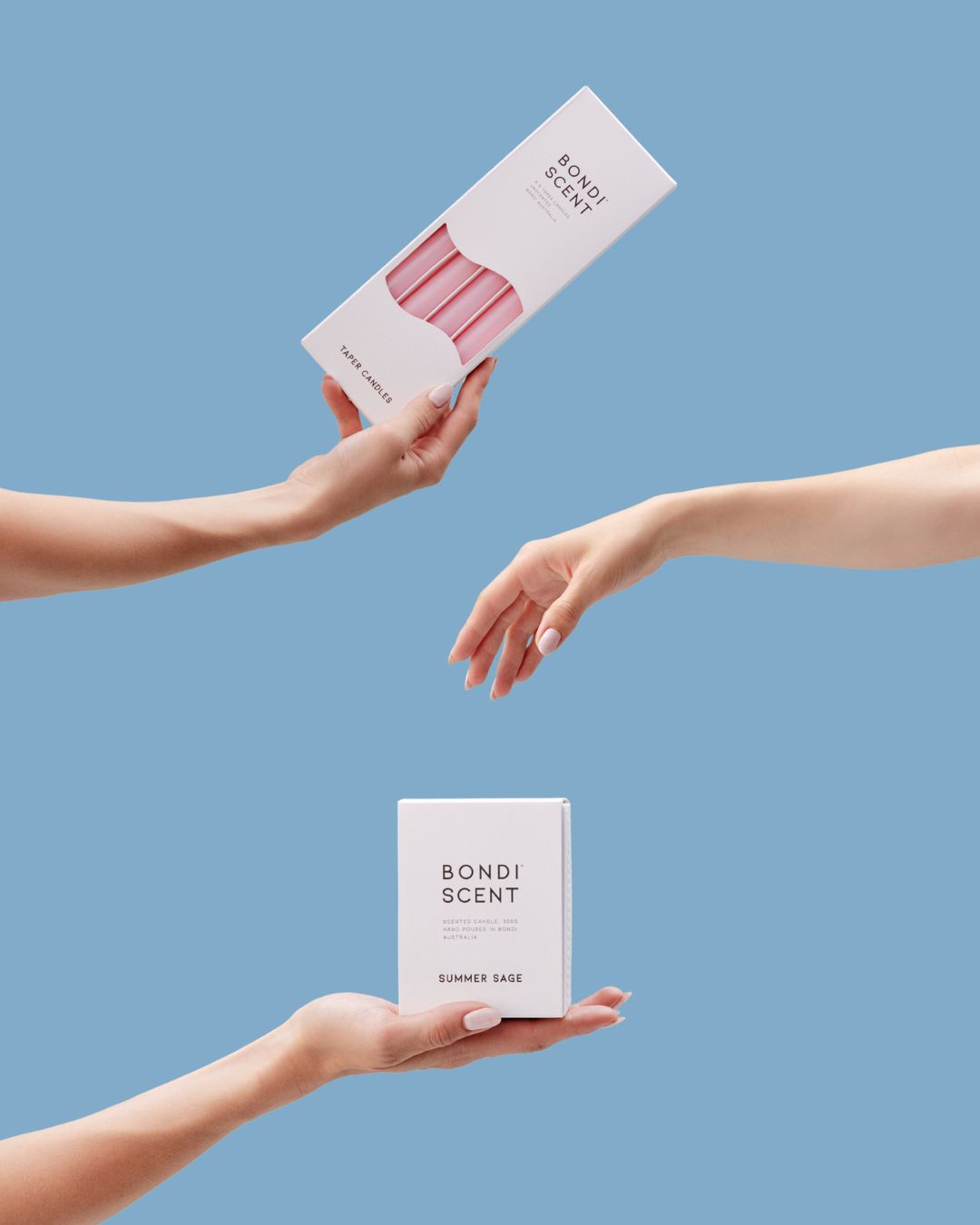 Bondi Scent dinner candles and Summer Sage candle box held between hands against blue background.