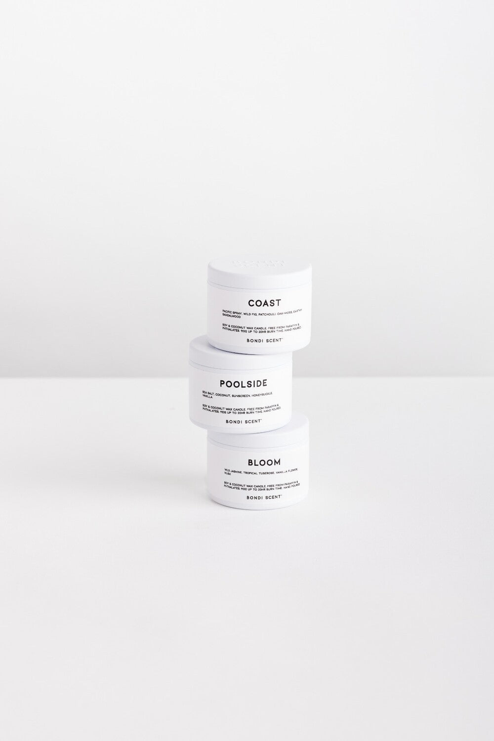 Three white cosmetic jars stacked vertically on a white surface against a white background. The labels read COAST, POOLSIDE, and BLOOM.