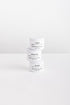 Three white cosmetic jars stacked vertically on a white surface against a white background. The labels read COAST, POOLSIDE, and BLOOM.