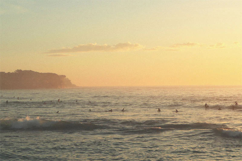 Ocean waves with surfers during golden hour