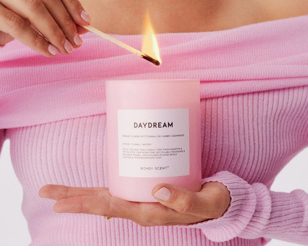 Bondi Scent 'Daydream' scented candle being lit with match held against person wearing pink clothing