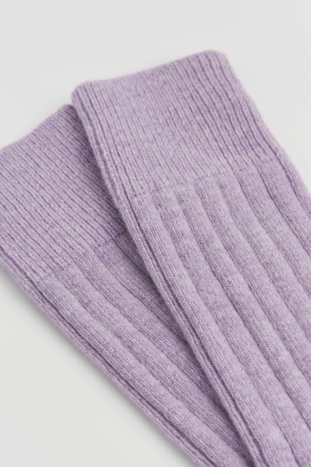 Purple ribbed merino wool socks on a light gray background