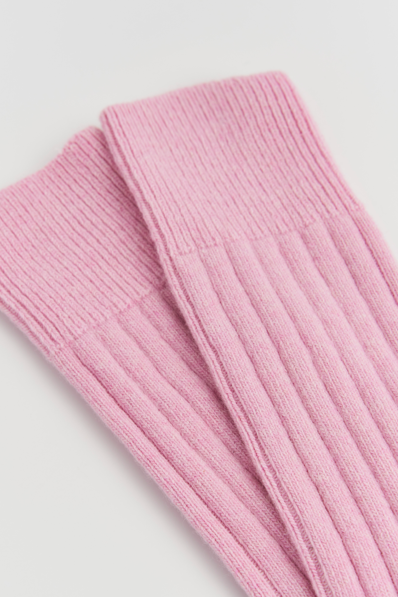 Close-up of pink ribbed knit socks on a light gray background