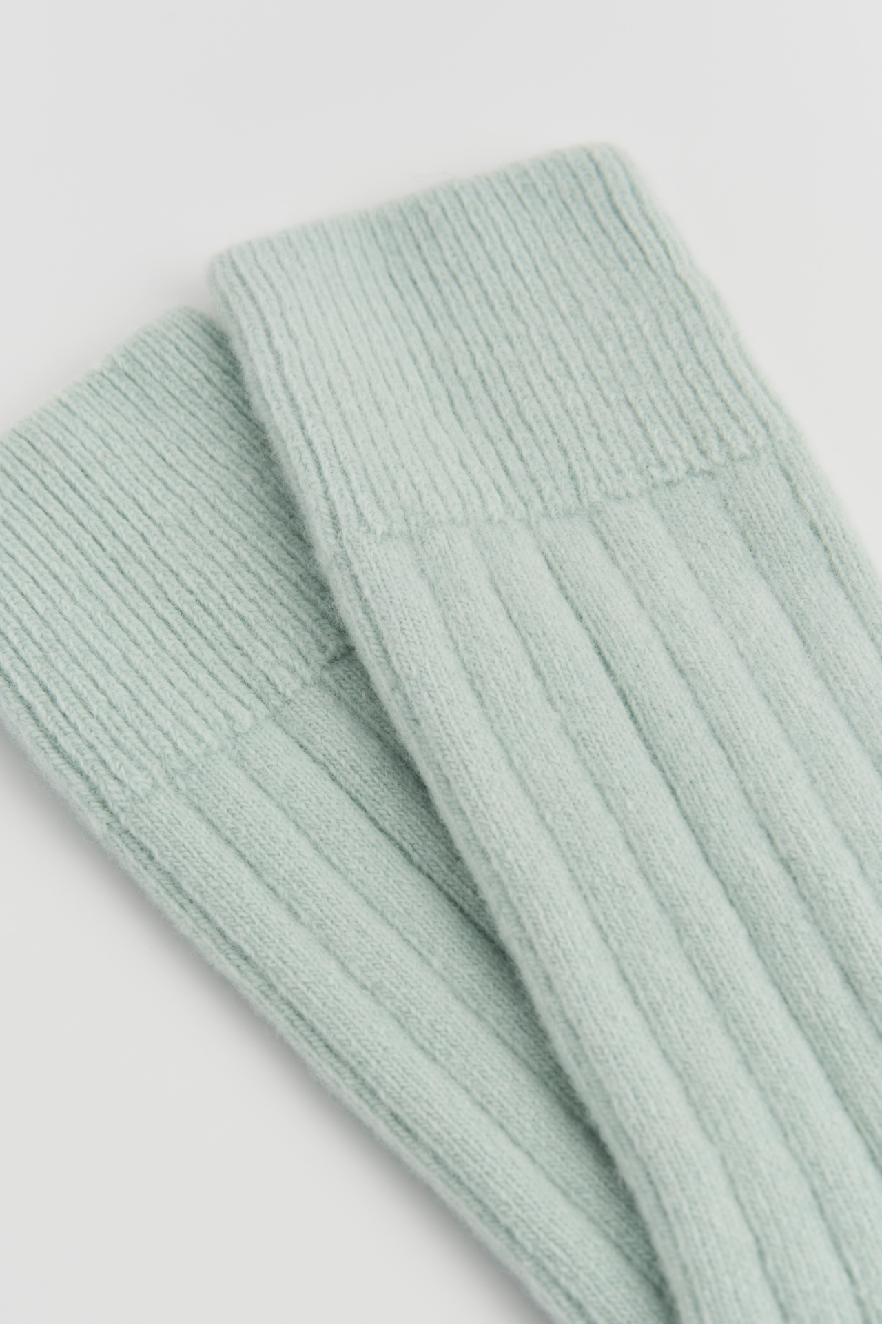 Light green ribbed knit socks on a light gray background