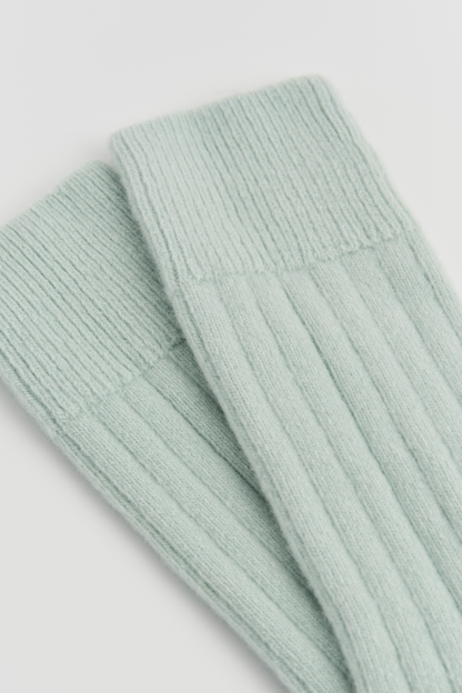 Light green ribbed knit socks on a light gray background